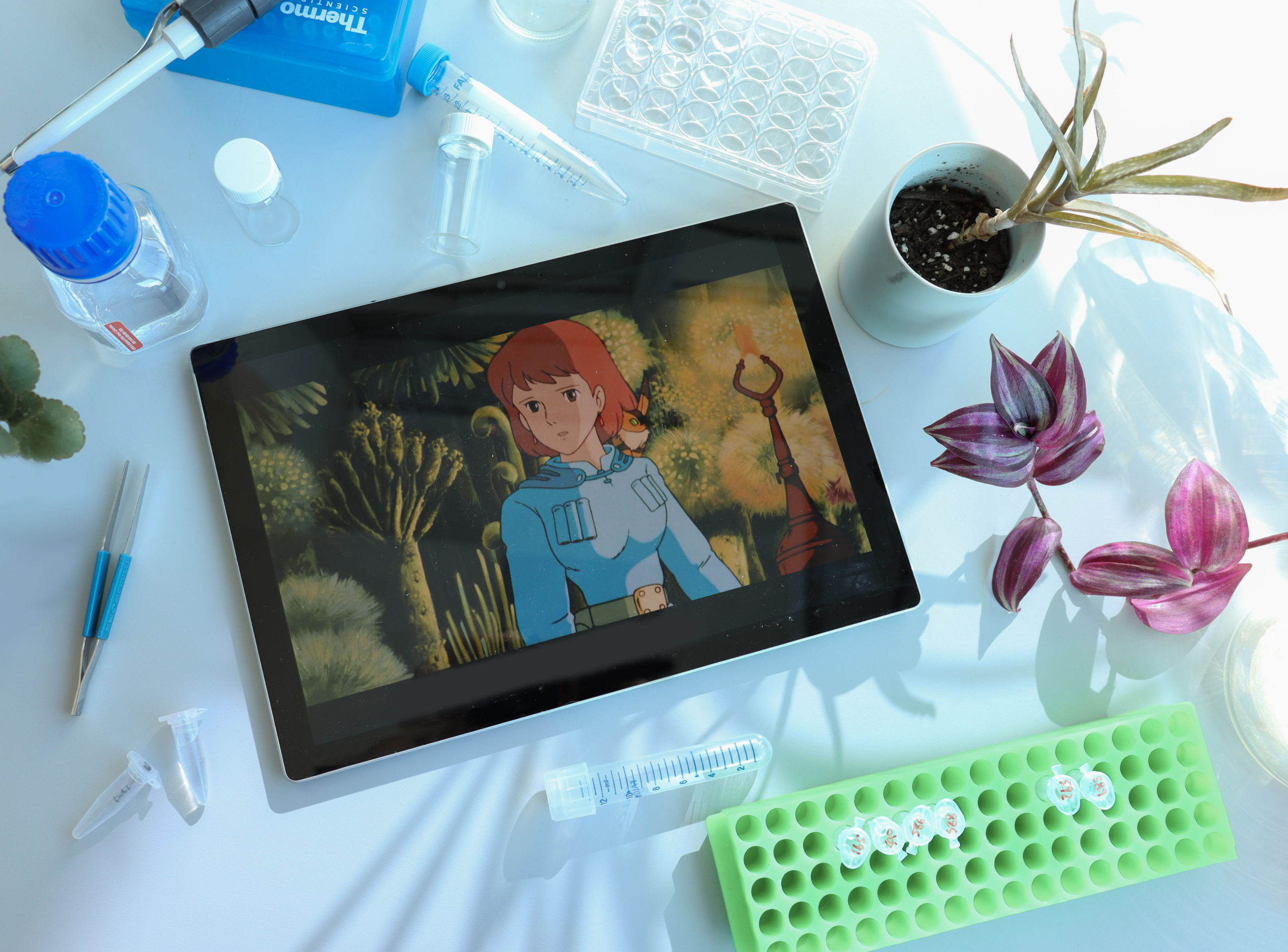 Photo of tablet with Nausicaa on screen surrounded by various science tools and plants